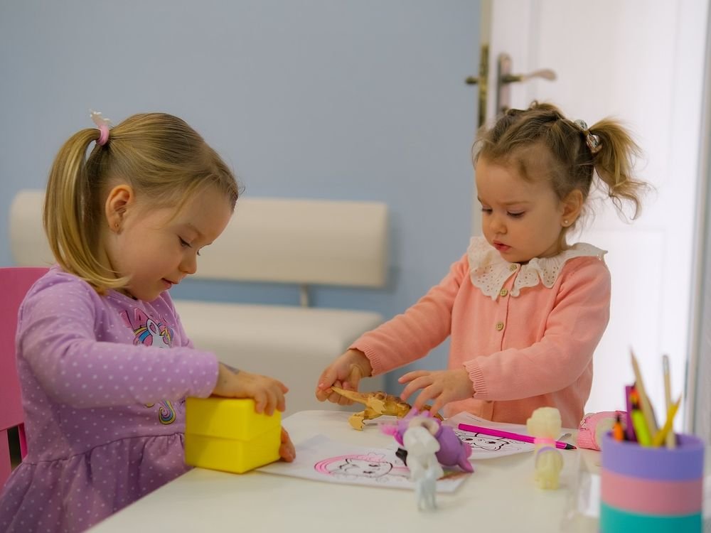 Дві маленькі дівчинки граються за дитячим столиком у медичному центрі
