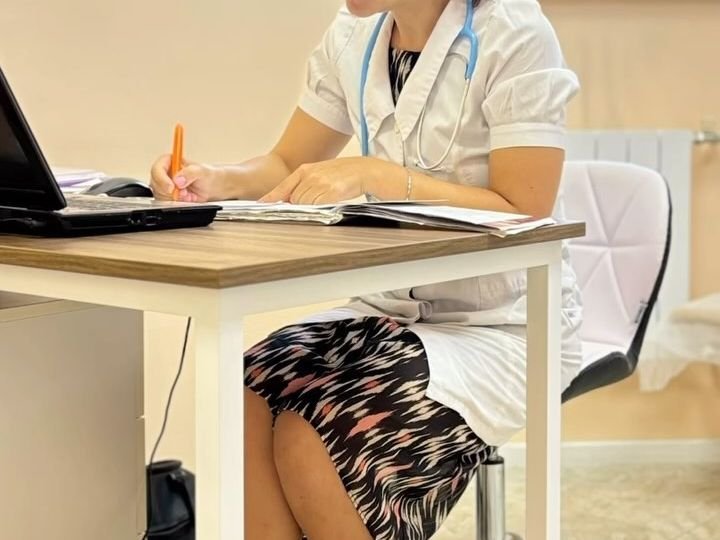 Педіатр заповнює документи за робочим столом