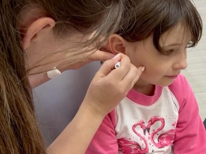 Лікарка проколює вушко дівчинці